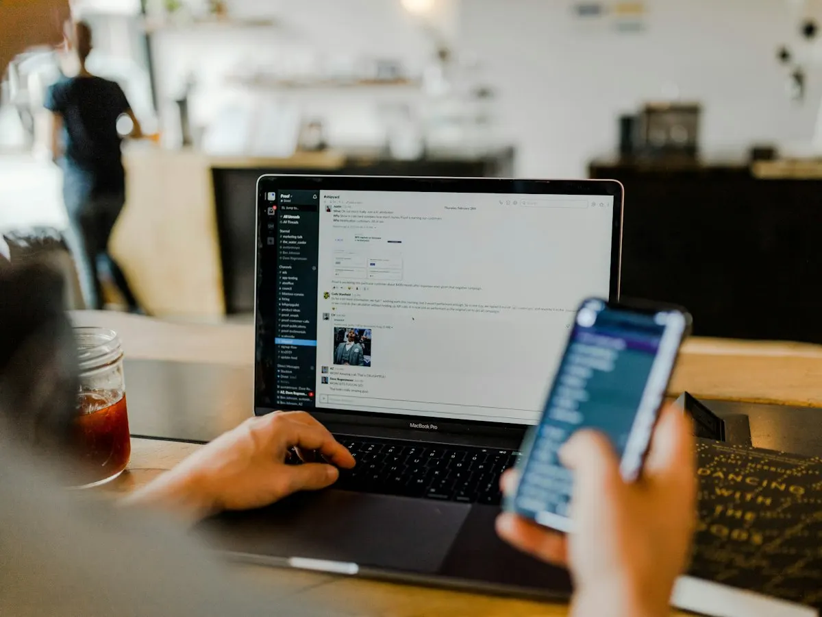 Social media manager scheduling posts on a laptop and phone
